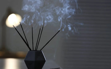 Burning incense sticks in a geometric holder with rising smoke for stress relief