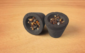 Two sambrani dhoop cups filled with resin on a wooden surface, incense for aromatherapy