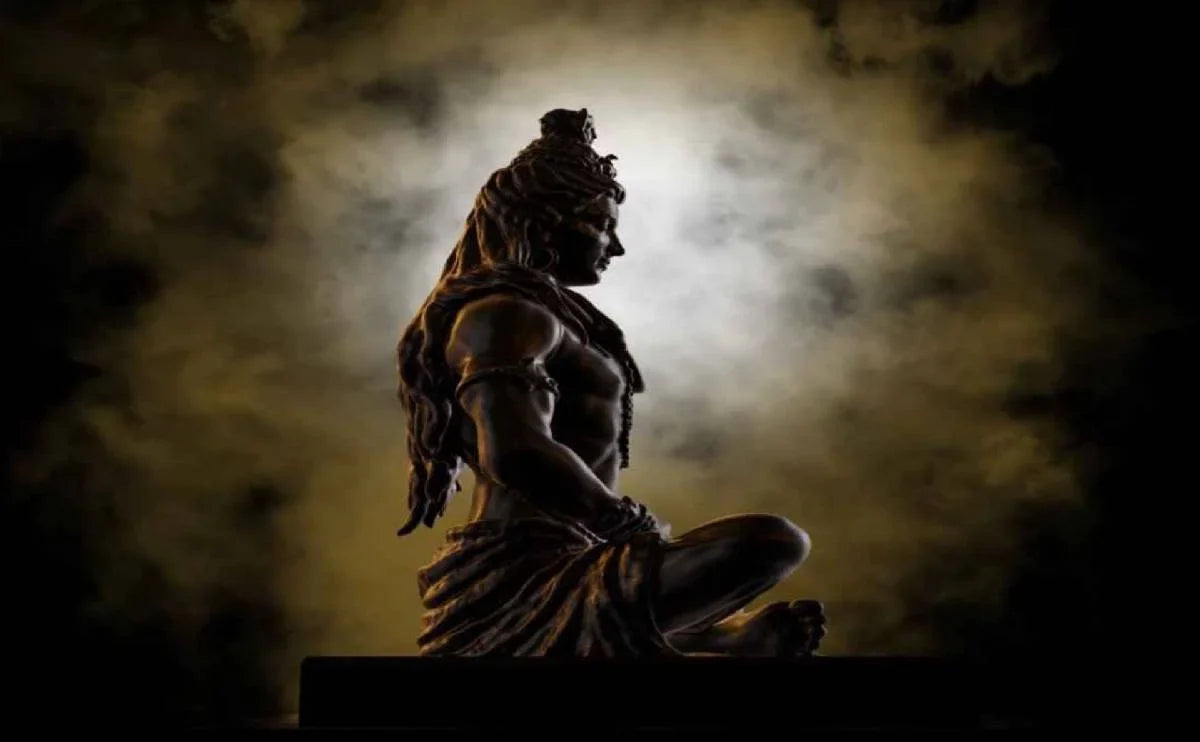 Bronze statue of Lord Shiva meditating against a smoky, mystical background